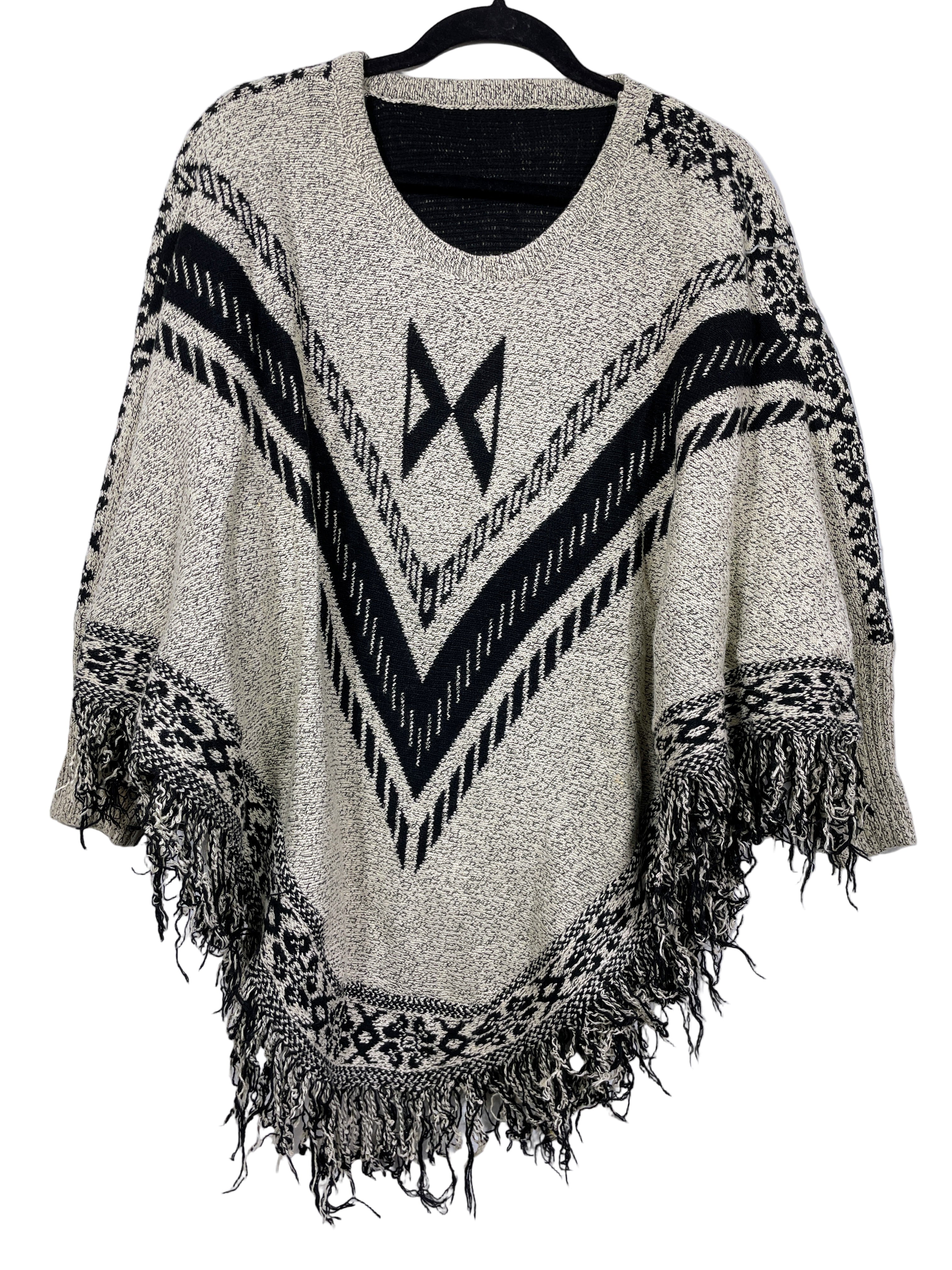 Cream and black sweater poncho with sleeves front view and fringe hem