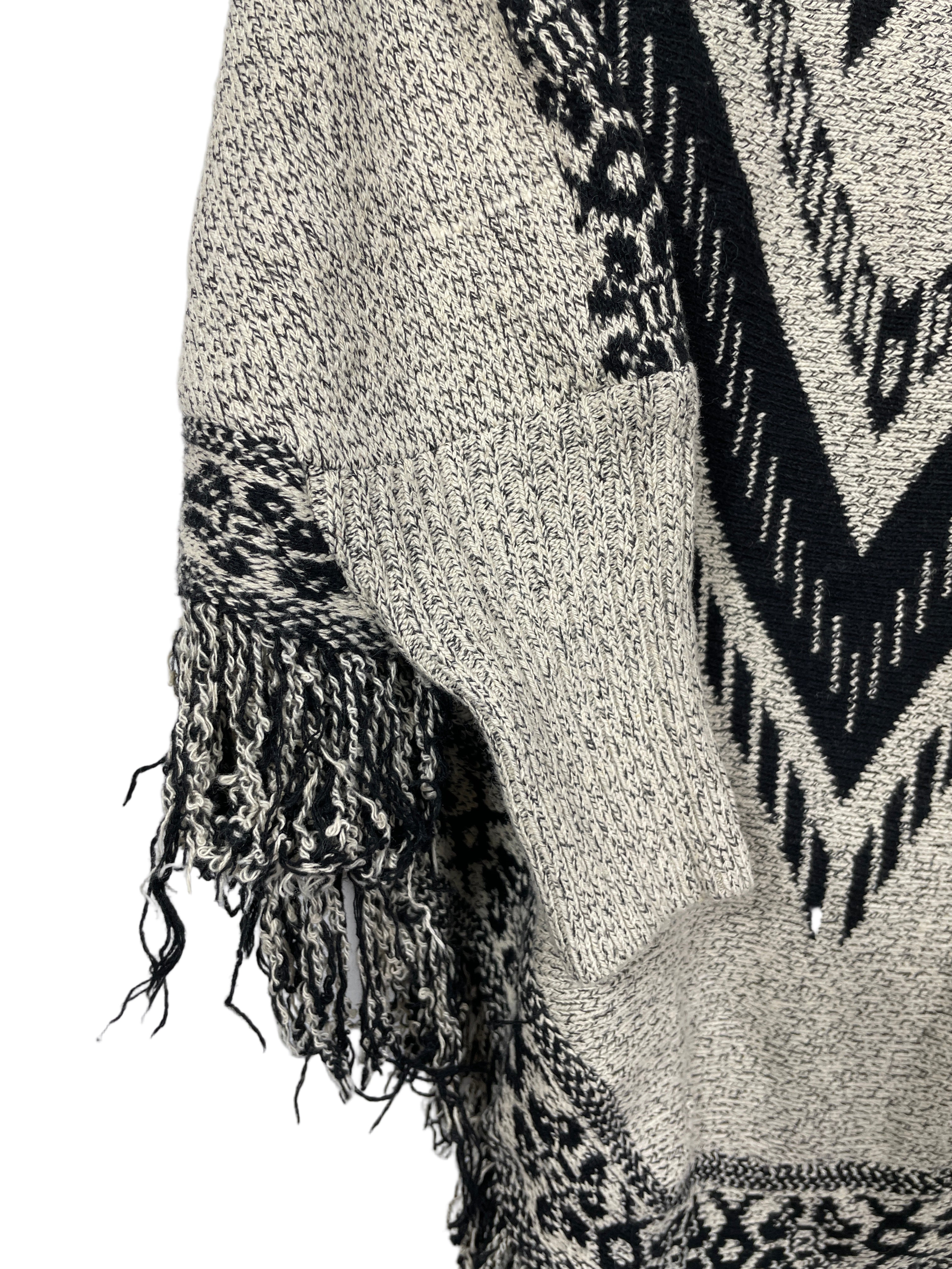 Sweater poncho side detail showing sleeve opening and fringe