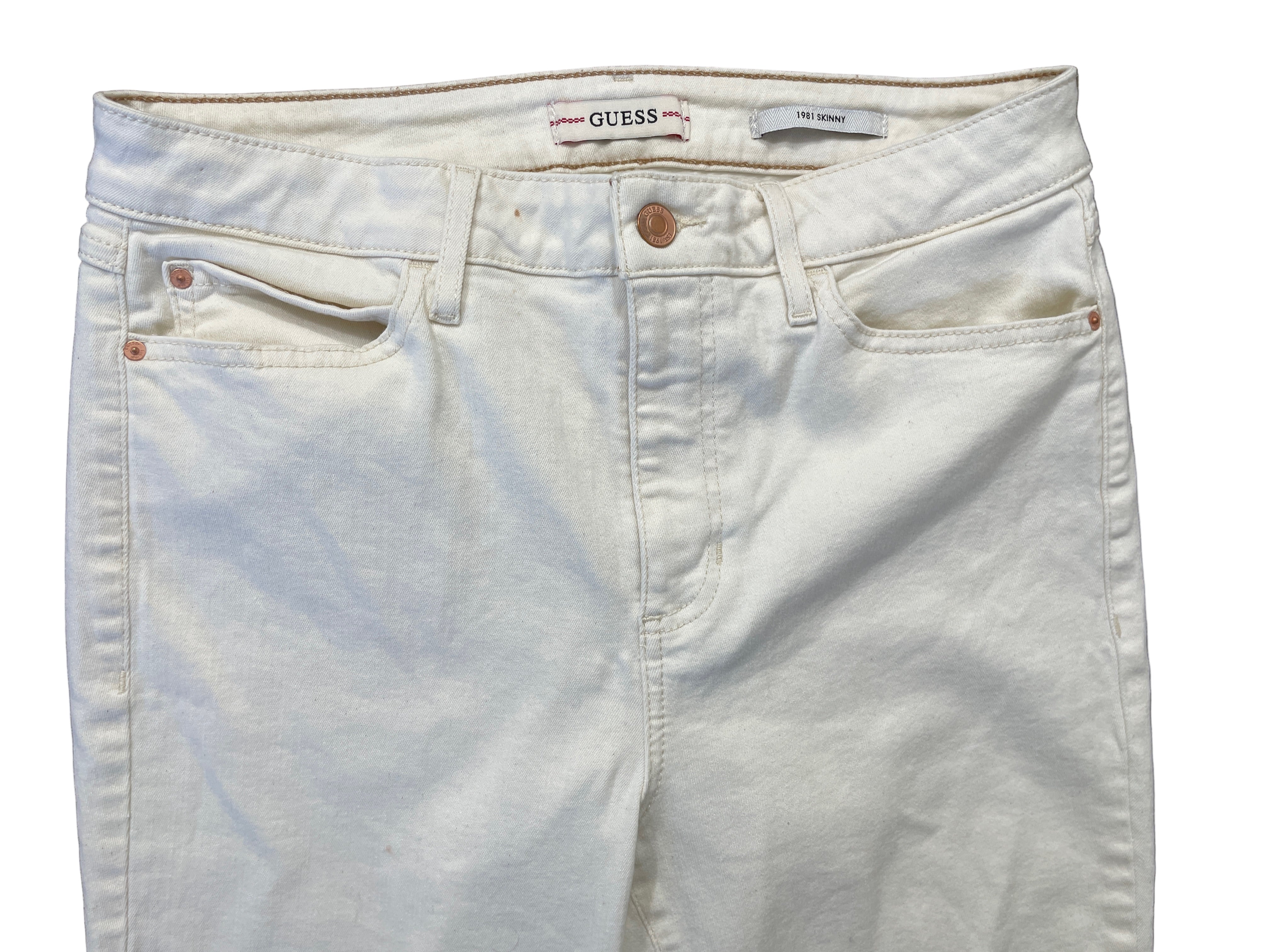 Front view of cream GUESS jeans showing zipper fly and five-pocket style.

