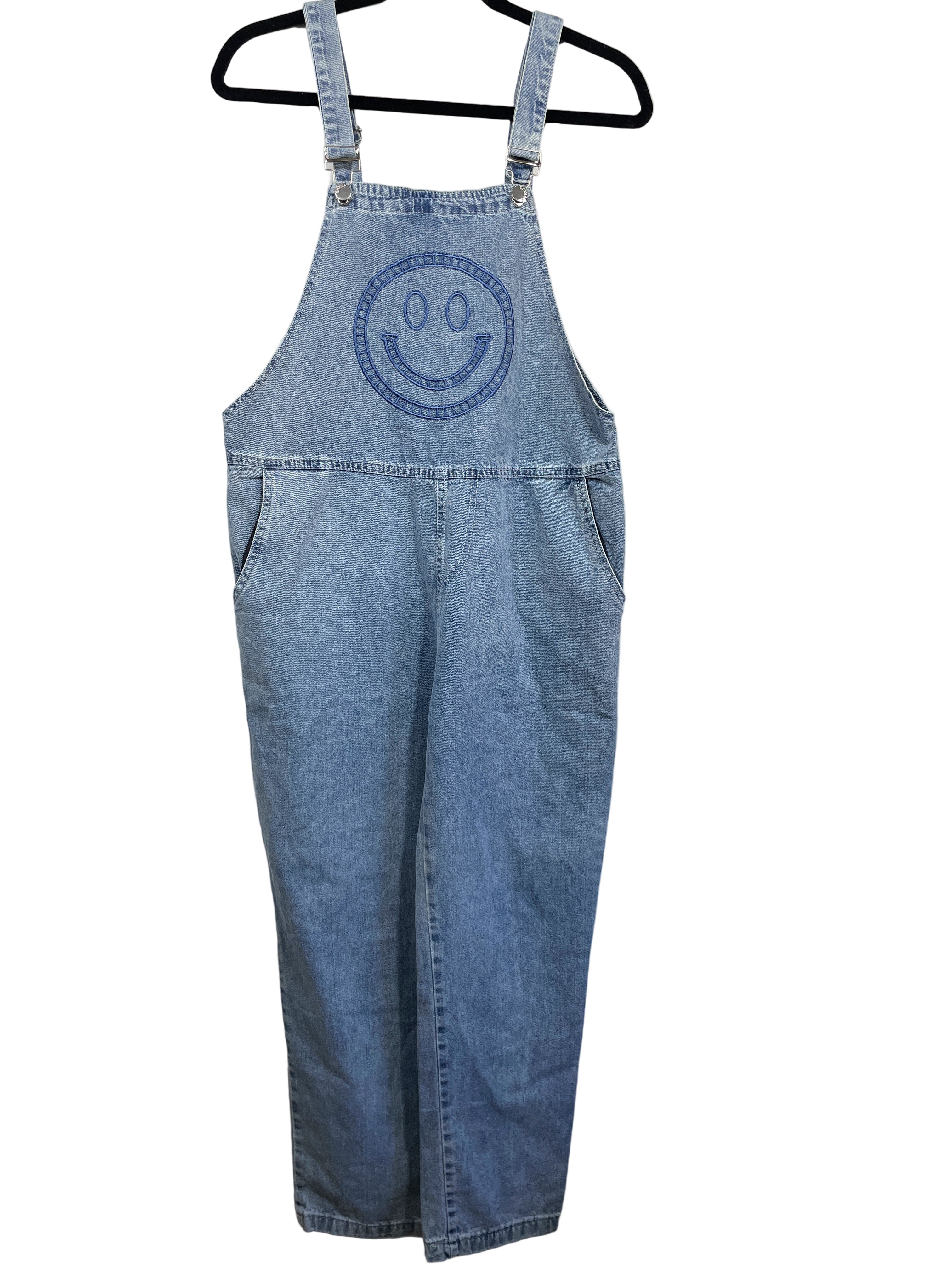 Blue denim overalls with a smiley face design on a white background
