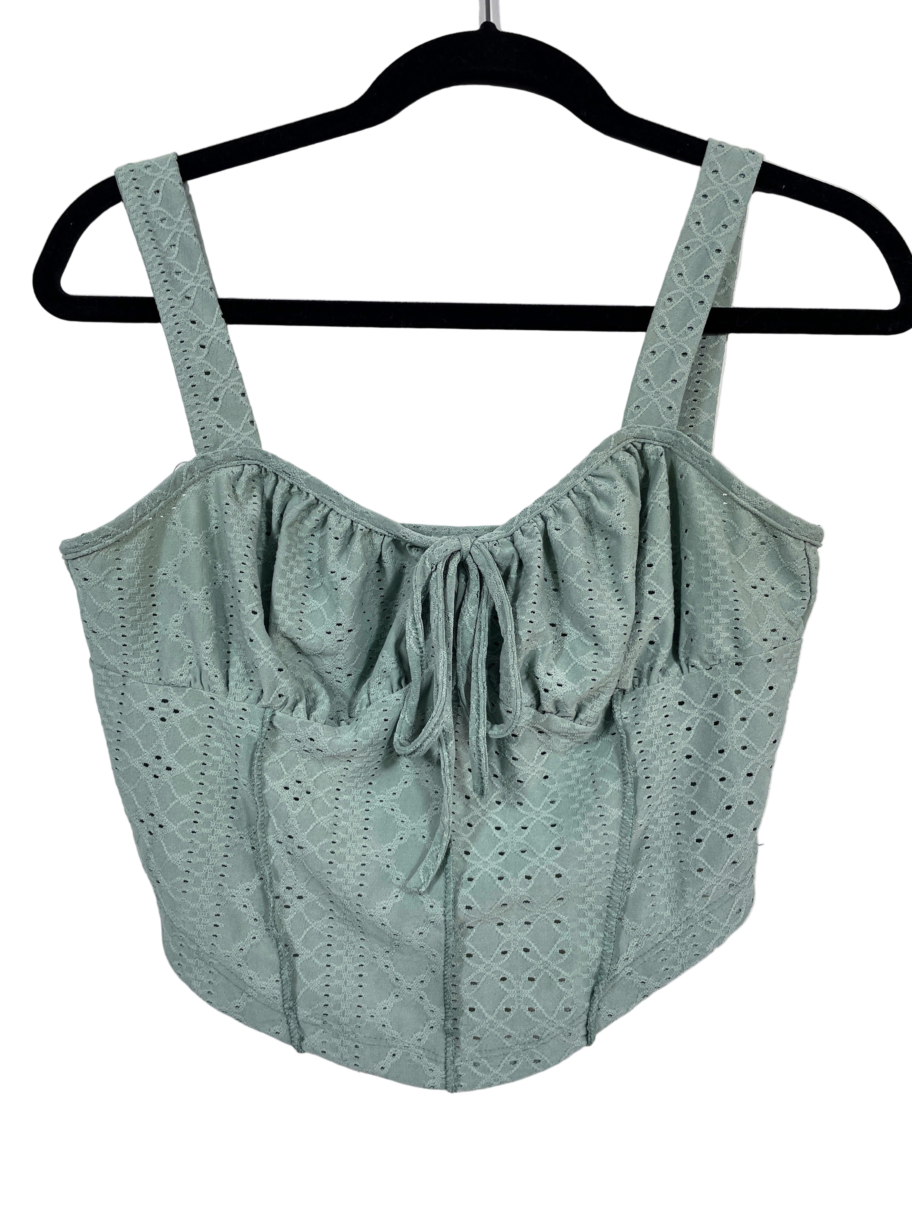 Green crop top with eyelet details on a hanger against a white background
