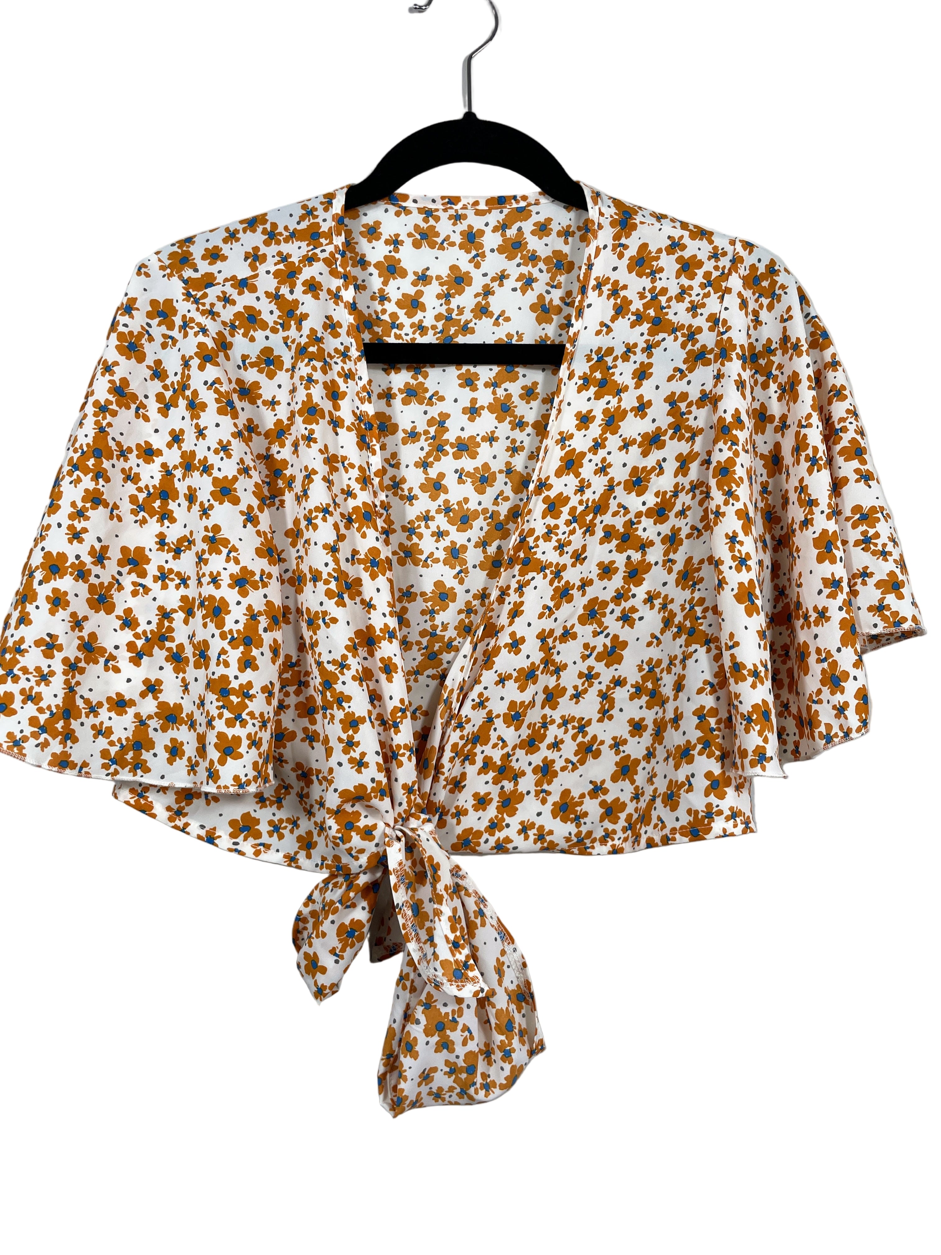 Front view of Joress floral tie-front blouse with orange and blue flowers on white fabric hanging on hanger.