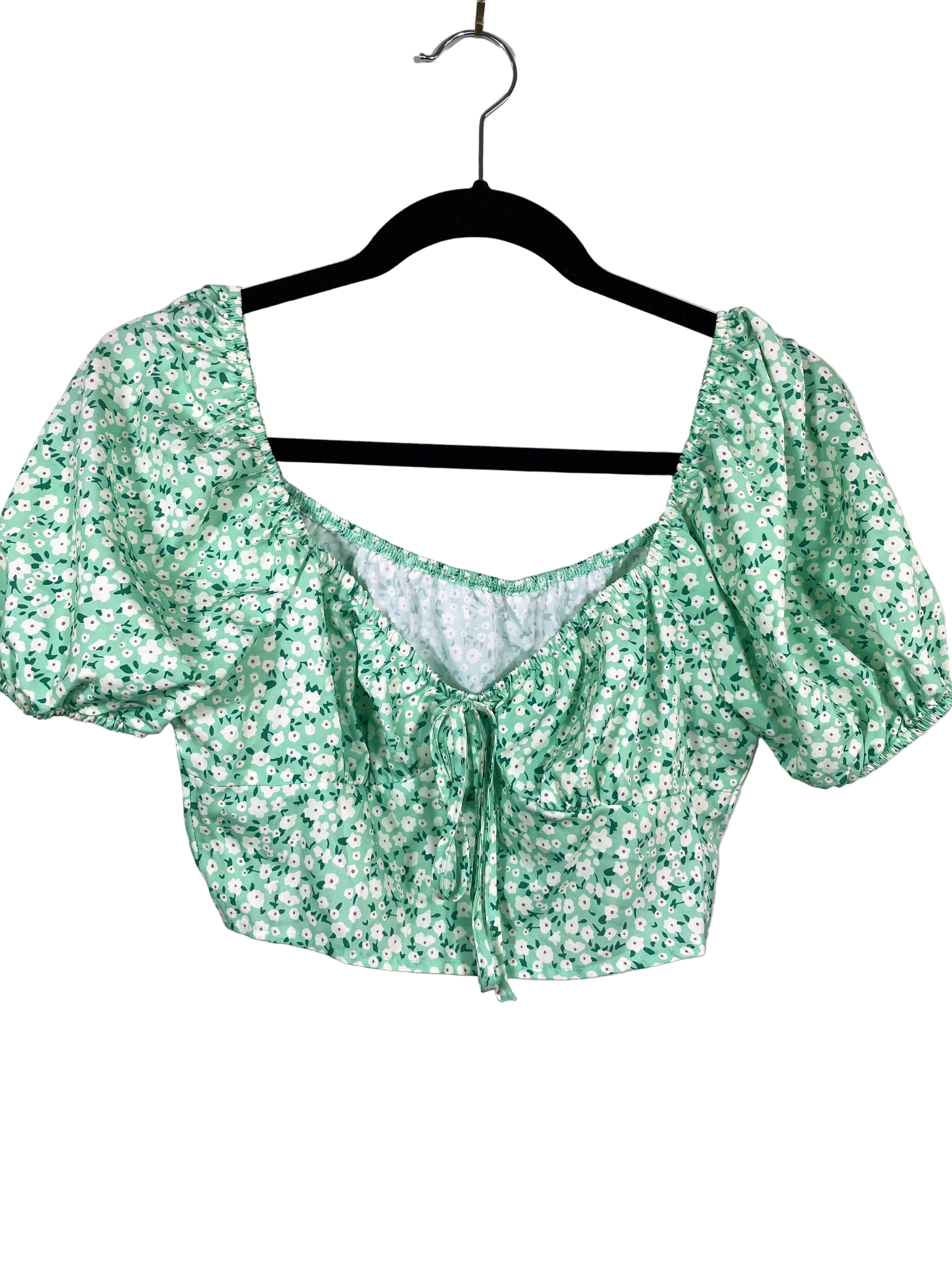 Green floral blouse on a hanger against a white background