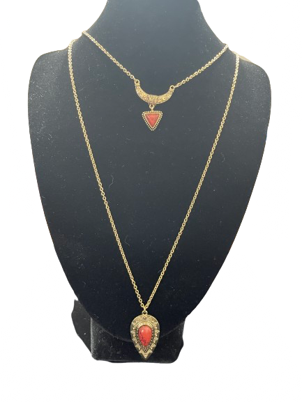 Two gold necklaces with red pendants on a black mannequin bust.