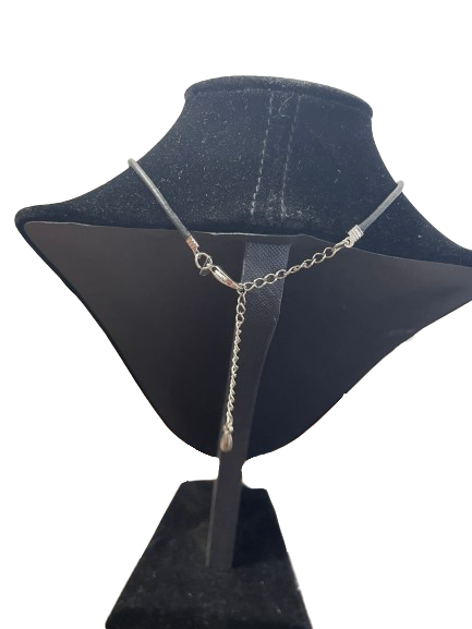 Silver necklace on a black mannequin bust against a white background