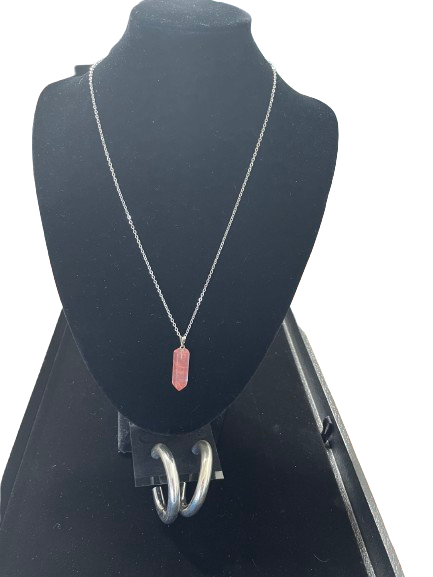 Necklace with a pink pendant on a black mannequin bust.