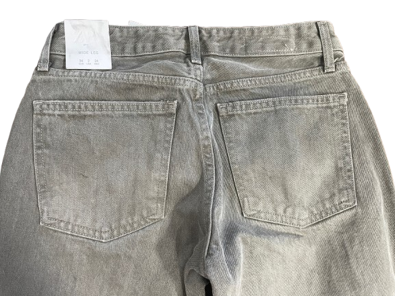 Back view of a pair of light gray washed denim jeans, showing the waistband, belt loops, and back pockets with a white size tag attached.