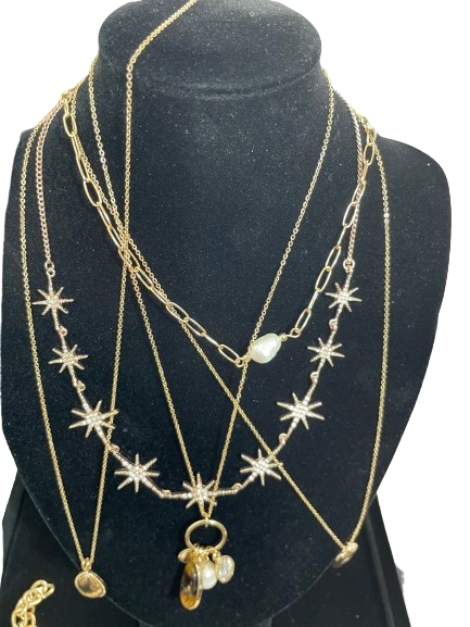 Six gold tone fashion necklaces layered on black jewellery display