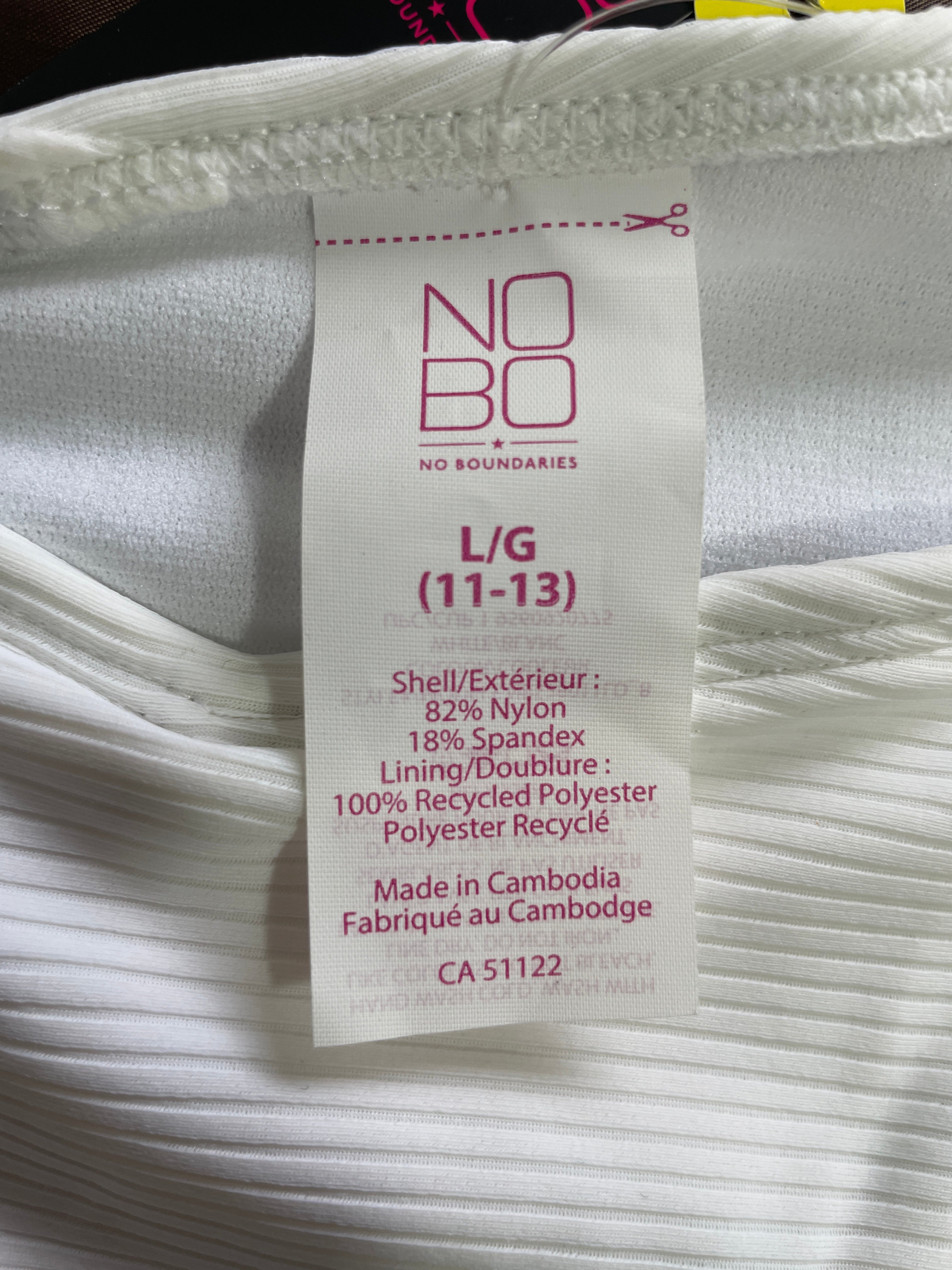 A close-up of a white garment tag reading NO BO / L/G (11-13) with fabric texture visible around it.