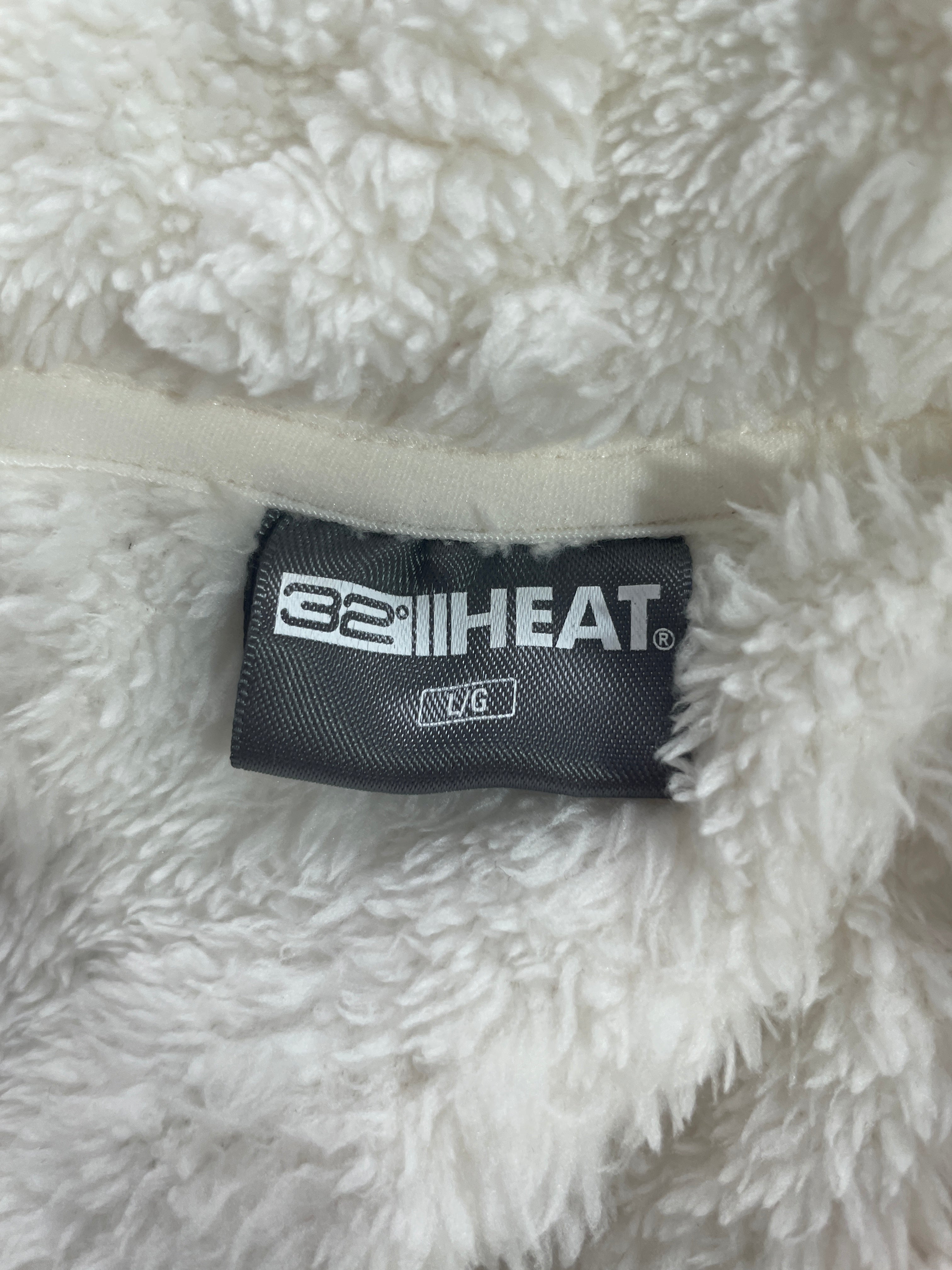 Close-up of a white sherpa fleece garment with a black 32F HEAT brand label sewn onto the inside collar.