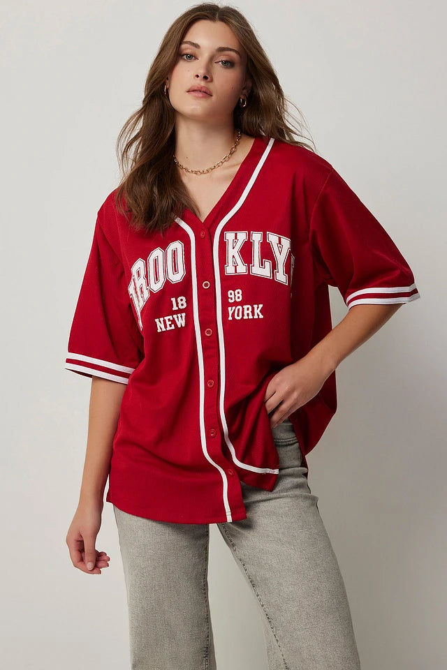Woman wearing a red baseball jersey with text on a plain background